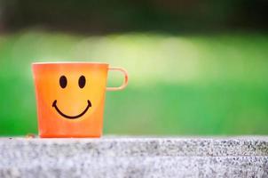 una taza de sonrisa naranja sobre la mesa foto