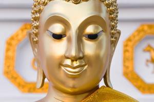 The beautiful face of golden Buddha image photo