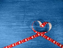 cinta roja en forma de corazón sobre un fondo azul de madera antiguo. símbolo de amor