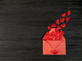 Red envelope with a heart on a black textured wooden background. Sending a message by mail. Valentine's day, birthday, photo