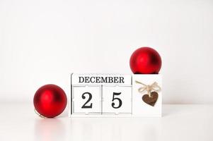 calendario con fecha del 25 de diciembre y cerca de bolas rojas de navidad. banner con lugar para texto foto