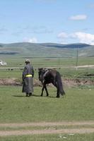 hombre irreconocible con ropa mongola tradicional caminando junto a su caballo foto