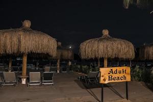 Signboard with deckchairs and parasols arranged at beach photo