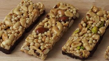 Cereal superfood energy bars with almond nuts, dry fruits, raisins chocolate on the wood table video