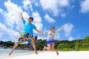 Father and daughter jumping on beach at Thailand photo