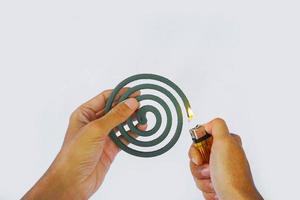 asian man's hand lighting mosquito coil isolated on white background. photo