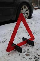 triángulo de advertencia rojo en el camino nevado de invierno, concepto de peligro foto