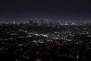 Aerial view of illuminated modern cityscape with sky in background at night photo