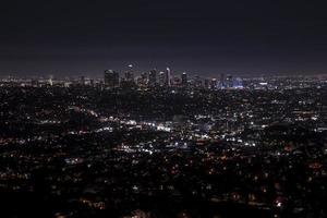 Aerial view of illuminated modern cityscape with sky in background at night photo