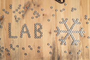 word laboratory and a snowflake are lined with metal nuts on a wooden table. Weather forecast. Creative idea. Top view. photo