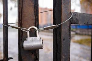 Closed padlock on an old metal rusty gate, outdoors, on a blurred background. photo