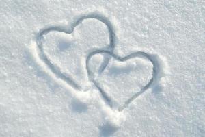 el símbolo de dos corazones dibujados en la nieve, en un soleado día de invierno. romance. día de San Valentín. copie el espacio. foto