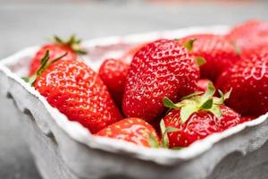 deliciosas fresas aromáticas en un recipiente de papel, sobre la mesa. la baya roja madura está lista para comer. foto