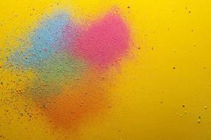 Multicolored, bright powder scattered on a yellow background. Copy space. Abstract texture. Top view. photo