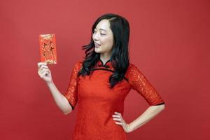 Asian woman holding red money fortune envelope blessing Chinese word which means May you have great luck and great profit isolated on red background for Chinese New Year celebration concept photo