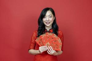 Asian woman holding red money fortune envelope blessing Chinese word which means may you have great luck and great profit isolated on red background for Chinese New Year celebration concept photo