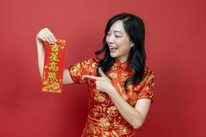 Asian woman holding red fortune blessing Chinese word which means to be blessed by a lucky star isolated on red background for Chinese New Year celebration concept photo