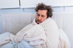 Sick day at home. Handsome Man has fever and common cold. Cough. Closeup Of Young Man Caught Cold Or Flu Illness. Portrait Of Unhealthy man Feeling Pain In Throat. photo