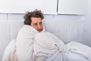 día de enfermedad en casa. hombre guapo tiene fiebre y resfriado común. tos. primer plano de un joven atrapado por un resfriado o una enfermedad gripal. retrato de un hombre malsano que siente dolor en la garganta. foto