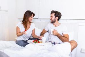 desayuno romántico en la cama hombre preparado para su mujer, ella estaba muy feliz, joven hermosa pareja en la cama desayunando y tomando café en la cama foto
