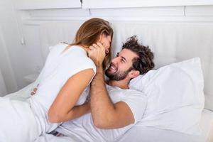 Beautiful loving couple kissing in bed. beautiful young couple lying together on the bed. photo