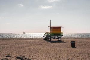 Colorful lifeguard hut on sand at Venice beach with view of sea and sky photo