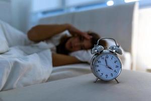 young beautiful woman at home bedroom lying in bed late at night trying to sleep suffering insomnia sleeping disorder or scared on nightmares looking sad worried and stressed photo