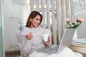 Excited woman reading good news on laptop screen at home and drinking coffee. Happy female chatting, shopping online, writing email, scrolling network, watching video on computer. photo