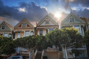 Historic victorian style houses and trees under cloudy sky at Alamo Square photo