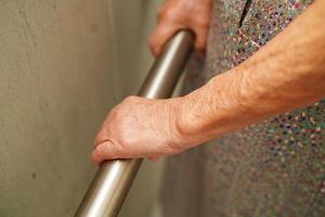 Asian elderly old woman patient use toilet support rail in bathroom, handrail safety grab bar, security in nursing hospital. photo