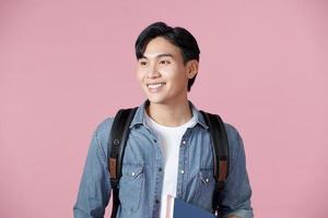 feliz estudiante sonriente de pie con mochila y carpetas sobre fondo rosa foto