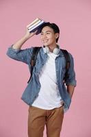 Smart guy student with backpack and bunch of books smiling at camera, copy space for advertisement over pink background photo