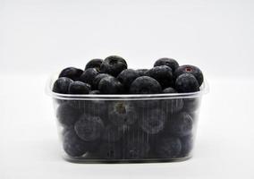 Delicious and juicy blueberries in a plastic container on a white background. Blueberries. photo