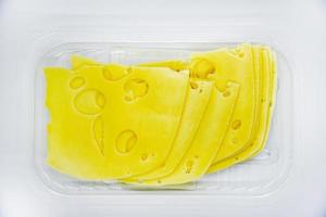 trozos de queso amarillo en rodajas con agujeros en el plato. primer plano de queso picado. deliciosas lonchas de queso. foto