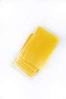Thinly sliced slices of cheese on a plastic backing. Delicious chopped yellow cheese. Cheese in a package from the store. photo
