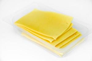 Thinly sliced slices of cheese on a plastic backing. Delicious chopped yellow cheese. Cheese in a package from the store. photo