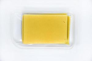Thinly sliced slices of cheese on a plastic backing. Delicious chopped yellow cheese. Cheese in a package from the store. photo