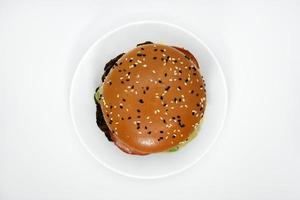 Hamburguesa doble de carne con verduras de fondo blanco. deliciosa hamburguesa con queso en un plato. comida rápida de carne. una hamburguesa grande con una chuleta doble. foto