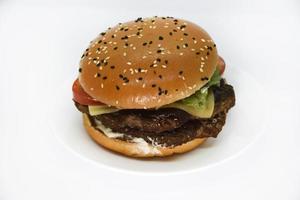 Double meat burger with vegetables on a white background. Delicious cheeseburger on a plate. Meat fast food. A large hamburger with a double cutlet. photo