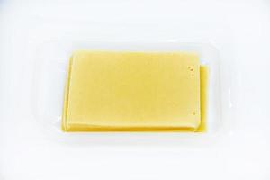 Thinly sliced slices of cheese on a plastic backing. Delicious chopped yellow cheese. Cheese in a package from the store. photo