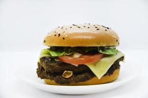 Double meat burger with vegetables on a white background. Delicious cheeseburger on a plate. Meat fast food. A large hamburger with a double cutlet. photo