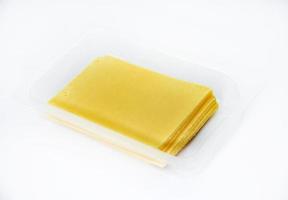 Thinly sliced slices of cheese on a plastic backing. Delicious chopped yellow cheese. Cheese in a package from the store. photo