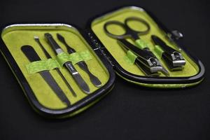 Green manicure set on a black background. Scissors and forceps for hand care. photo