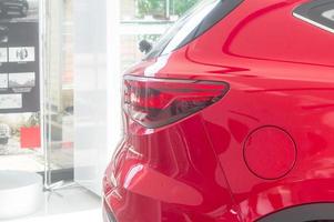 Close up rear part of red hatchback car with LED light in car showroom is tidily prepared for customer to see and try to drive. New model of red hatchback car with high technology ready for sale photo