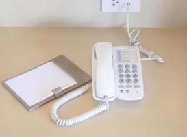 Telephone with note paper and pencil near bed served for guests in hotel room photo