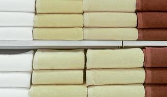 Beautiful colorful bath towels tidily folded on shelves in department store used as pattern background texture photo