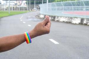 Hand wearing rainbow or lgbtq symbol wristband stretching in the air with mini heart symbol to campaign for protection and support on gender diversity or lgbtq people and community photo