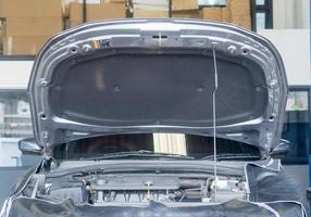 coche con capó abierto o capó del radiador para mantenimiento, aceite de motor o cambio de lubricador en el departamento de mantenimiento de la sala de exposición de coches en el centro de la ciudad foto