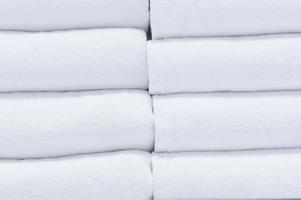 hermosas toallas de baño blancas cuidadosamente dobladas en los estantes de los grandes almacenes utilizadas como textura de fondo, salud y concepto de moda foto