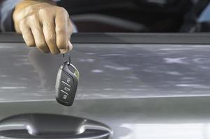 Seller handing over a key remote control to buyer from inside the car at showroom on delivery day after driving demonstration photo